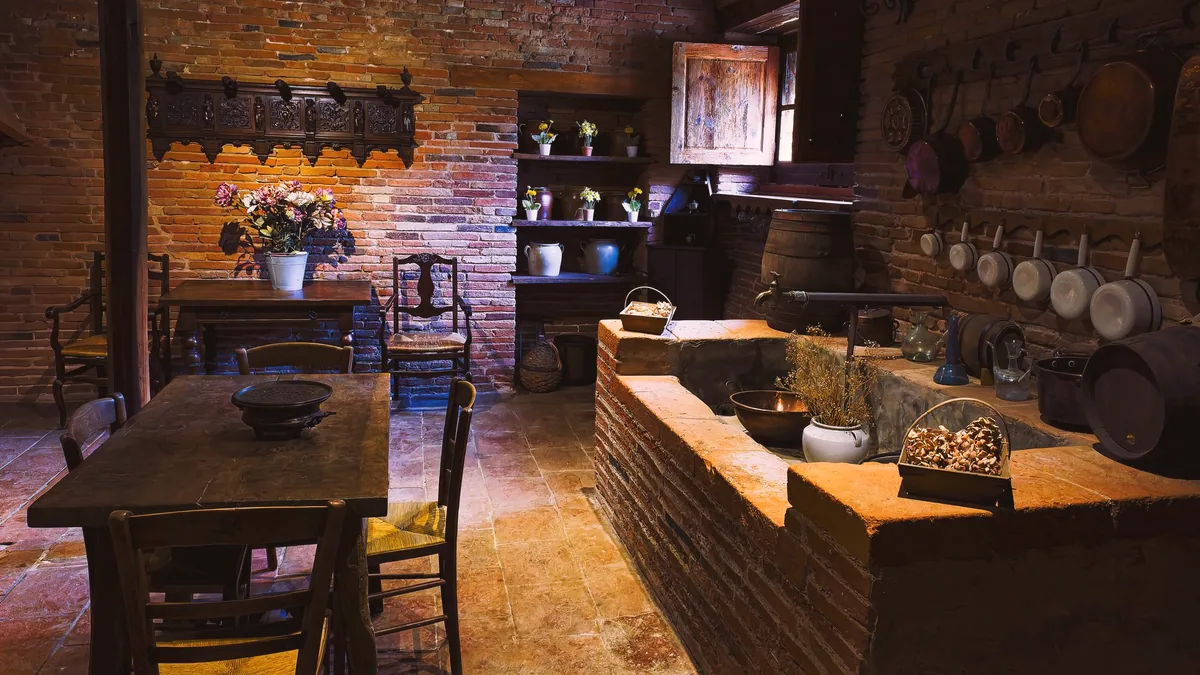 El interior de una taberna, con barra de madera y mesas al fondo.