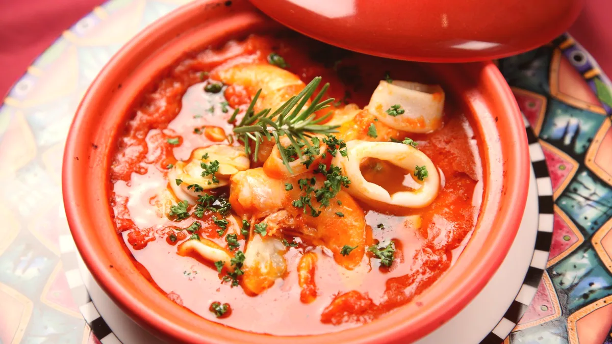 Un guiso de cefalópodo en salsa de tomate, servido en una cazuela.