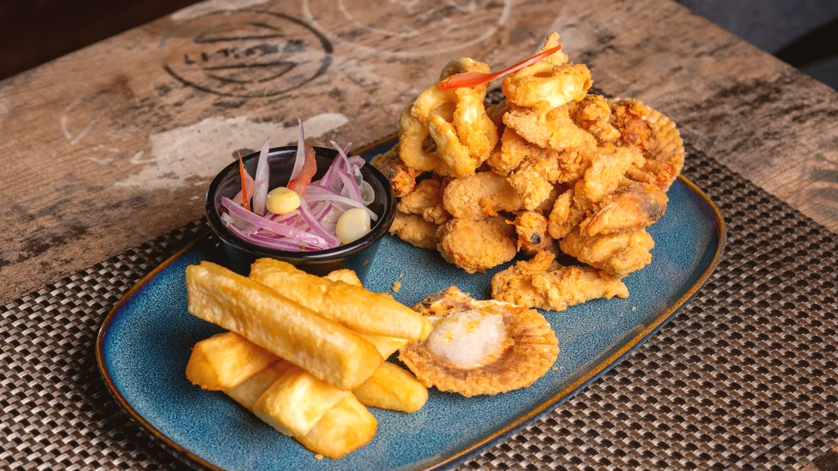 Un plato de pescado frito servido en el mostrador, bajo la luz de la barra.