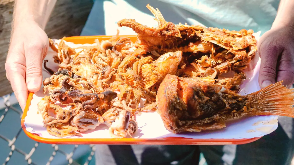 Una fuente de pescado frito, enharinado y recien sacado del aceite.