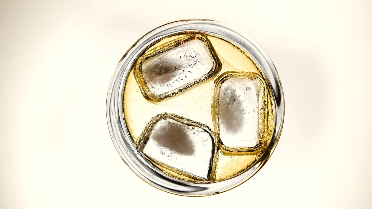 Un vaso corto con hielo y una bebida clara y fría.